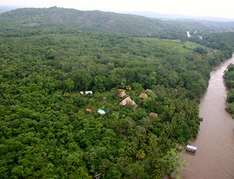 Aerial view of Mopan River Resort's thatched cabanas surrounded by jungle beside the Mopan River